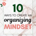 the words "10 ways to create an organizing mindset" superimposed on an image of rose gold metal hangers on a white marble tile background set in a herringbone pattern.