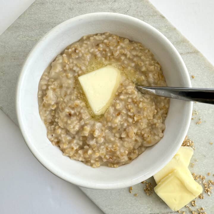 steel cut oatmeal in white bowl with pat of butter in center