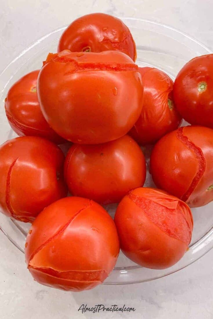 a glass pie plate filled with a pile of blanched tomatoes