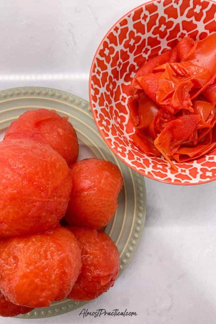 a pile of peeled tomatoes on a plate next to a bowl of discarded tomato skins