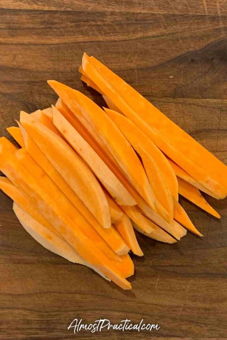 raw sweet potatoes cut into fries on a cutting board