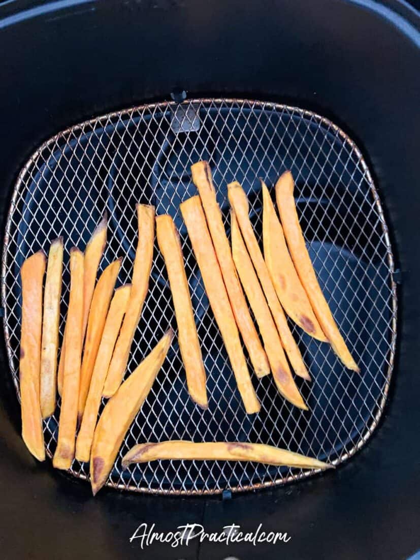 Sweet potato fries in air fryer basket at 3 minute mark.