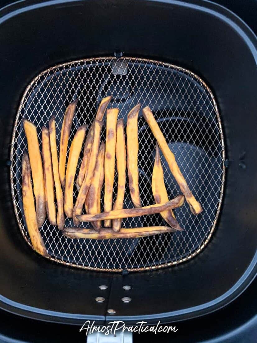 Sweet potato fries in air fryer basket at 6 minute mark.