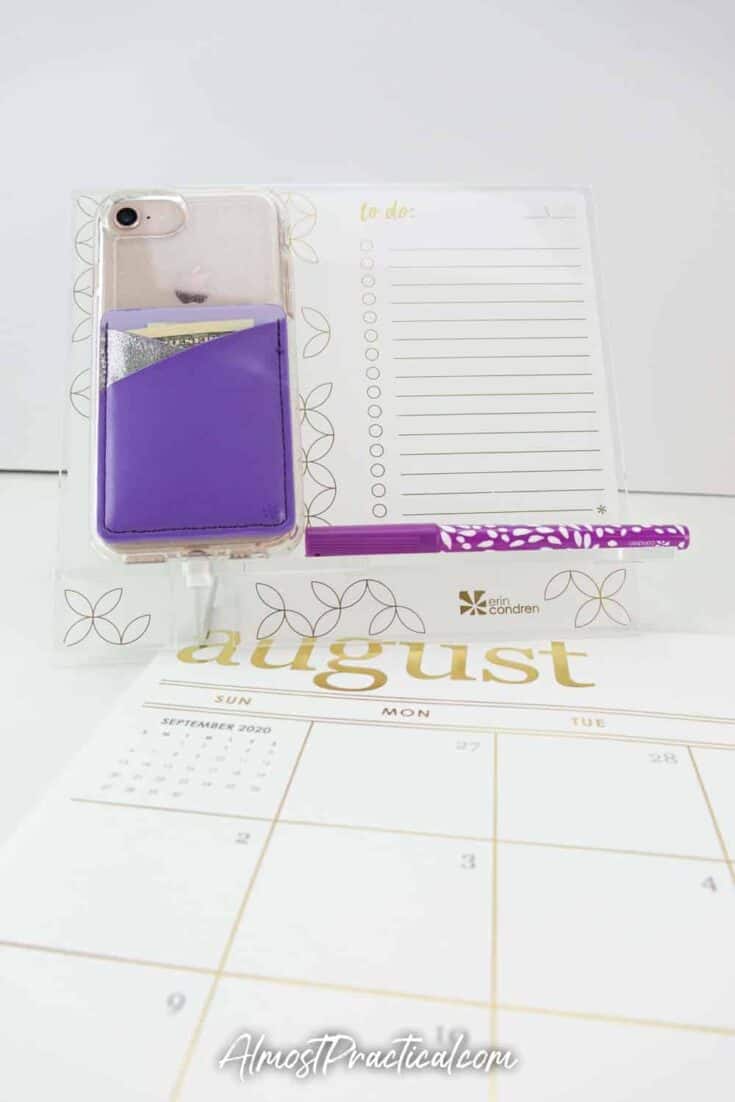Erin Condren Acrylic Desk Stand and phone holder, with iPhone on it and adhesive phone pocket in purple attached to phone.