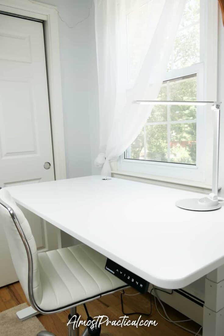 White standing desk with lamp on top.