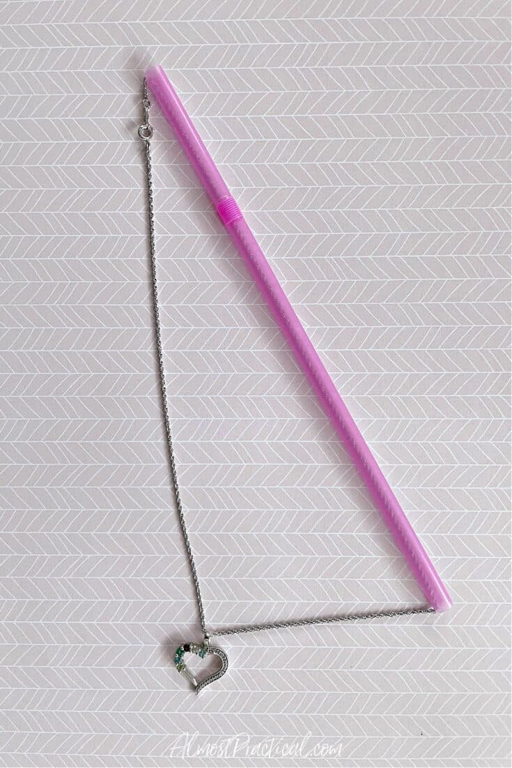 necklace threaded through a pink plastic drinking straw