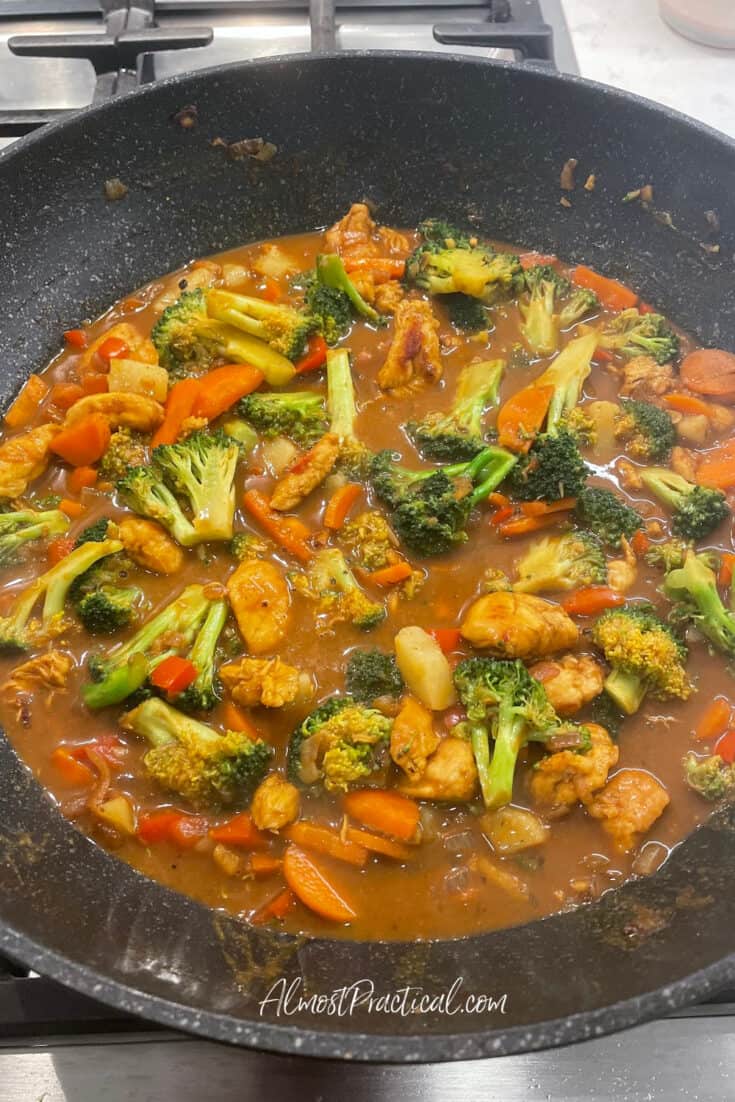 a wok with chicken, broccoli, and vegetables cooked in brown sauce