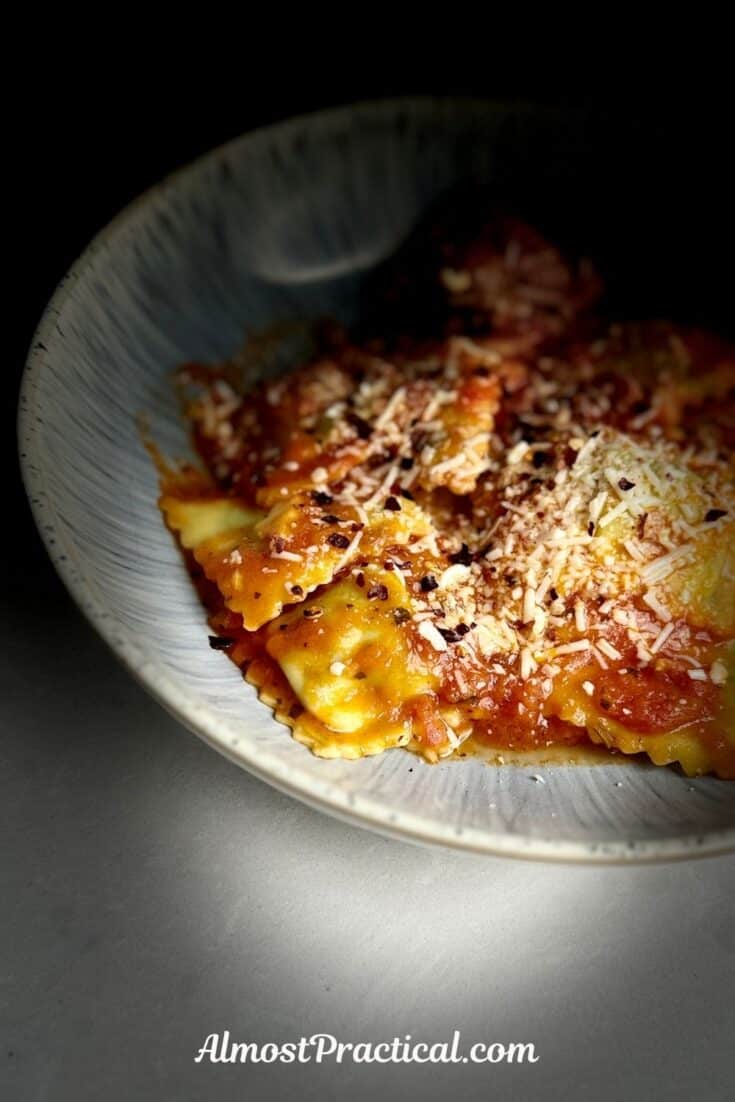 bowl of ravioli with sauce and sprinkled with cheese.