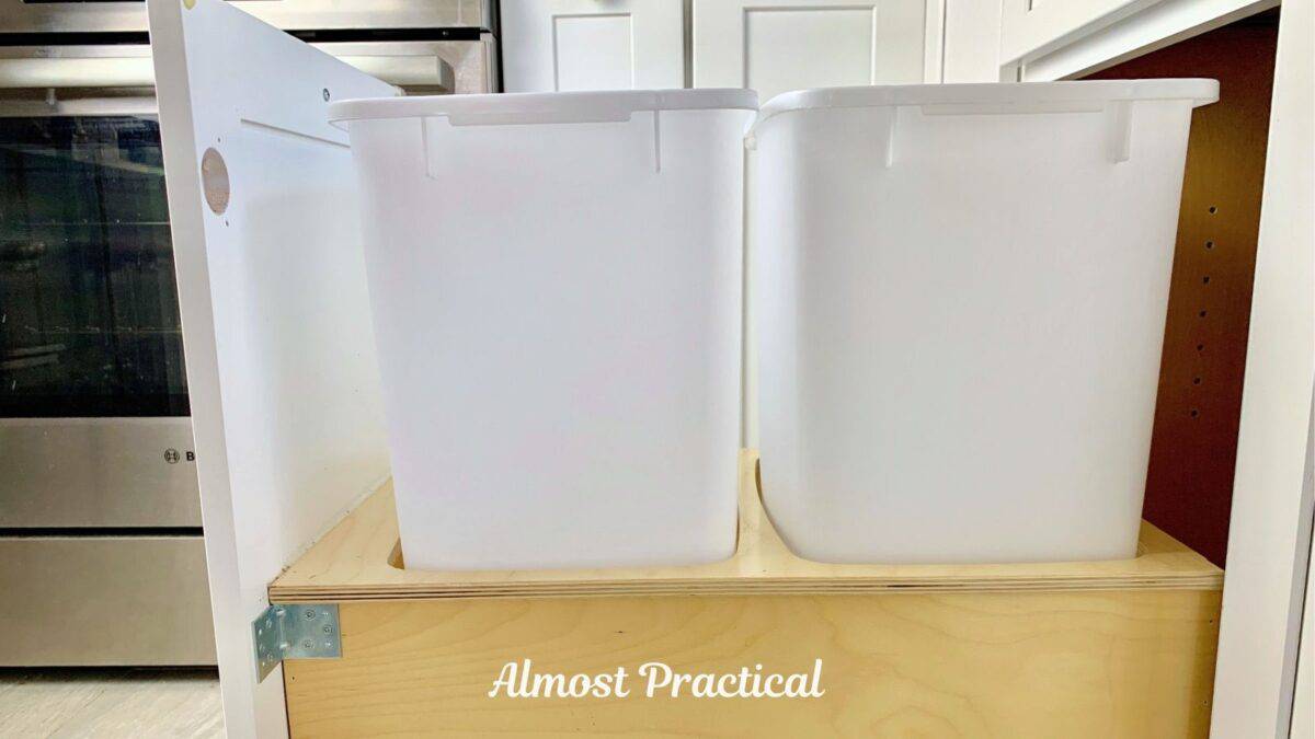 pull out kitchen trash can cabinet side view with two medium sized white kitchen trash cans.