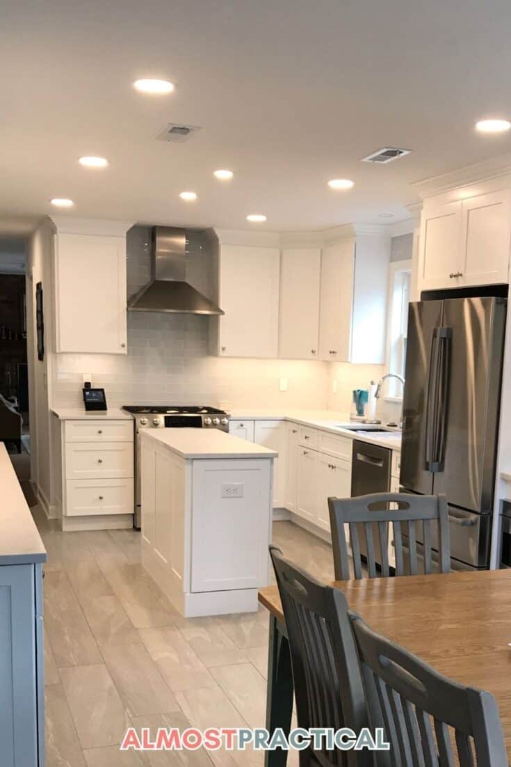 photo of kitchen with white cabinets and small island with recessed lights on