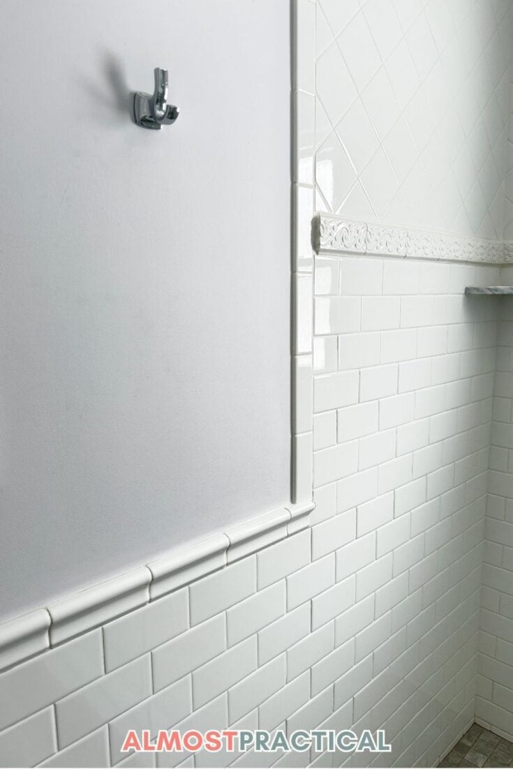 white subway tile on lower half of bathroom wall with hook above