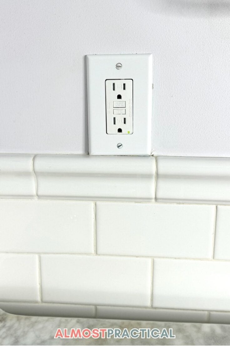 wall outlet above subway tile wainscot on bathroom wall