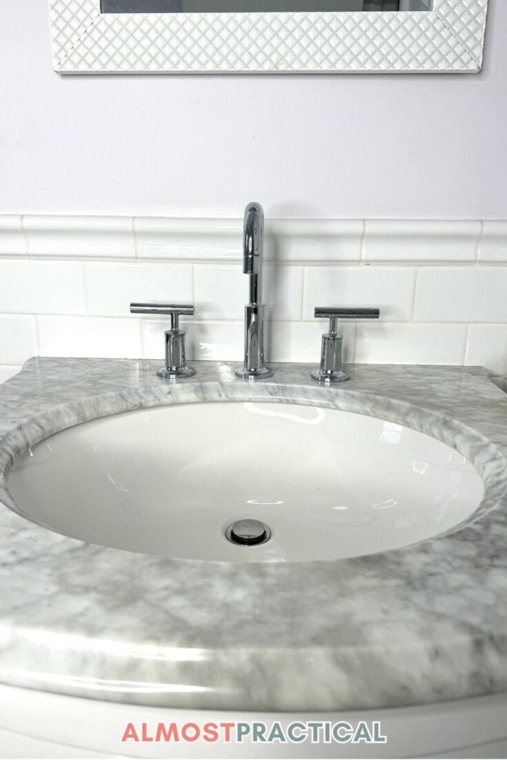 oval bathroom faucet and sink on marble top vanity with white subway tile backsplash