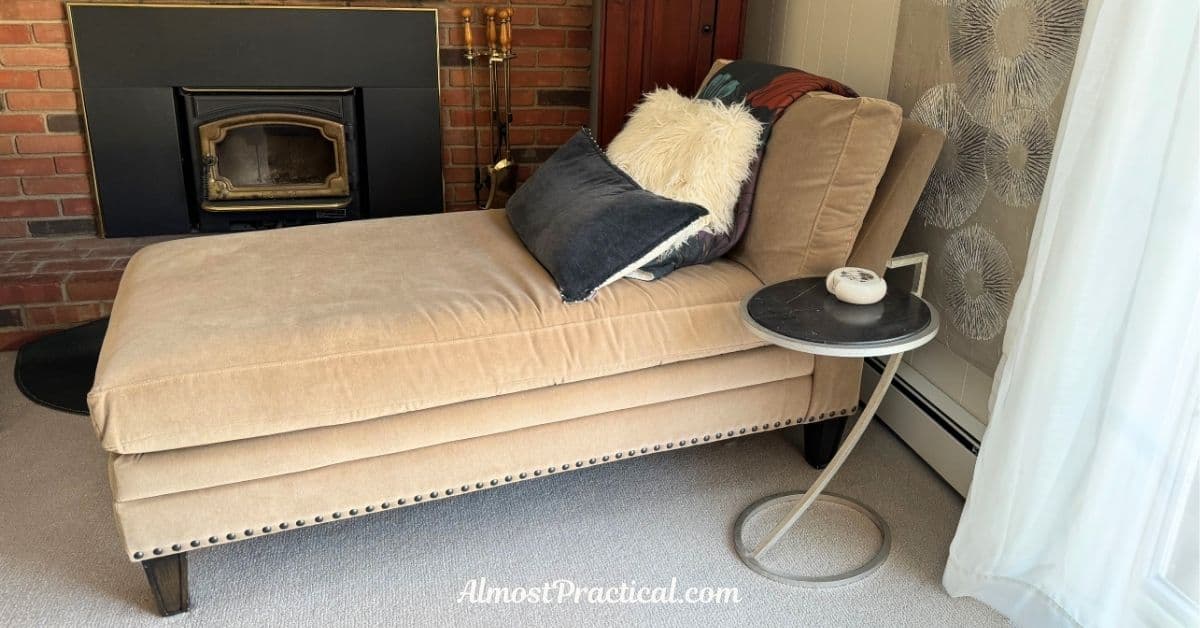 a beige chaise lounge with black accent pillow and a small side table in the foreground