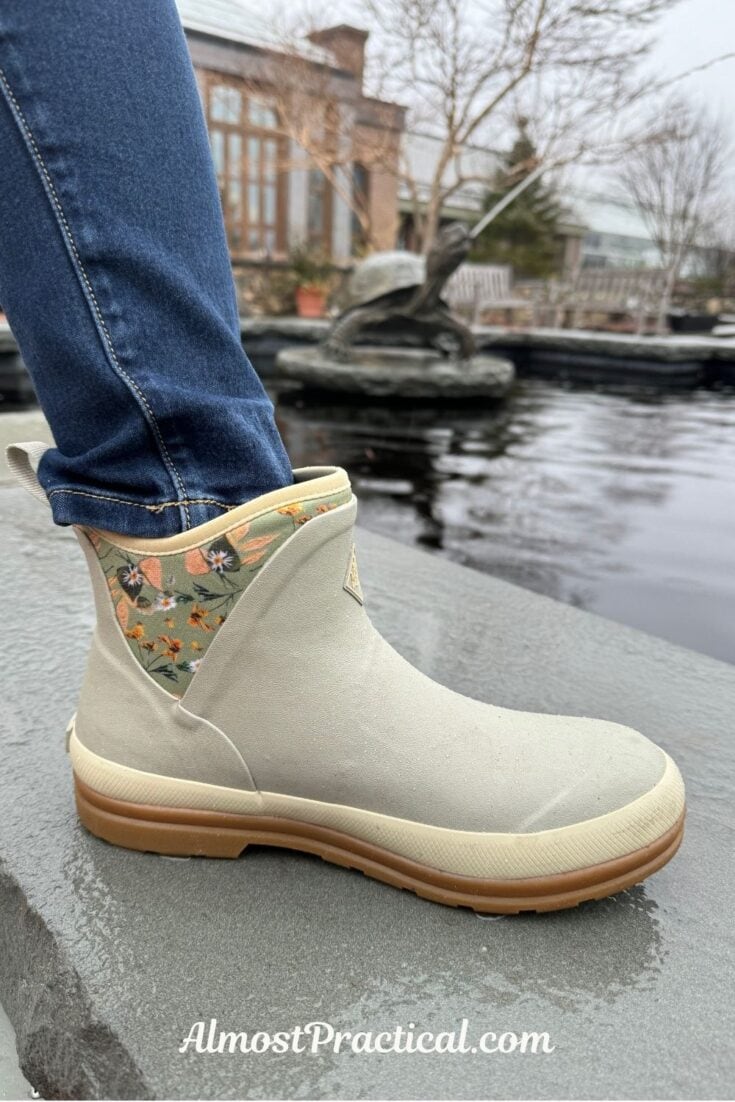photo of person wearing jeans and gray ankle Muck Boots on a rainy day