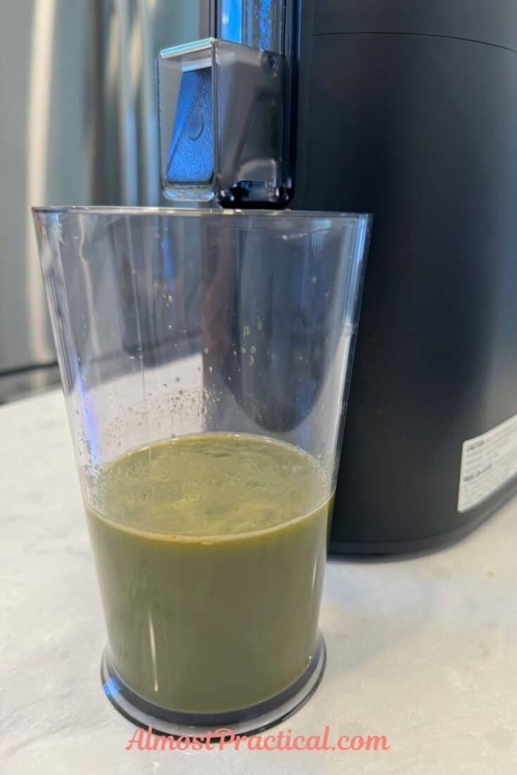 glass of green juice in front of a Hurom H400 juicer