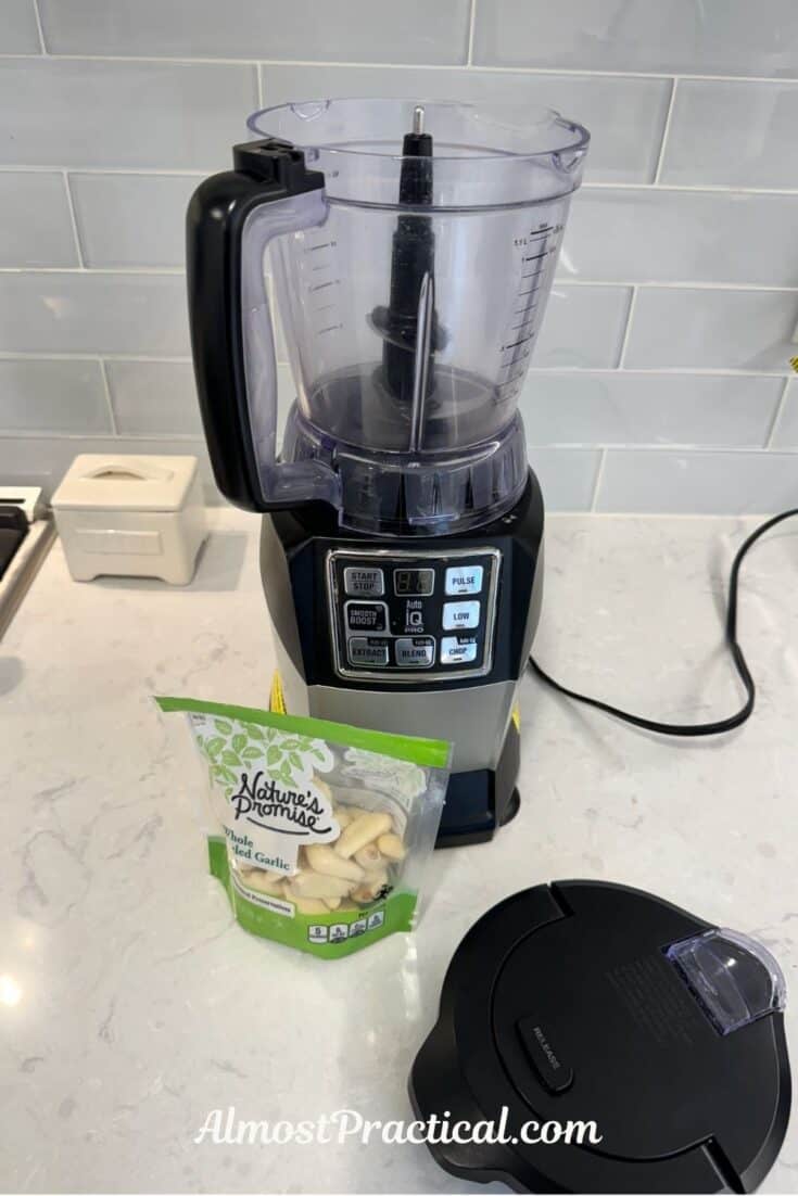 food processor with a bag of peeled garlic cloves in front