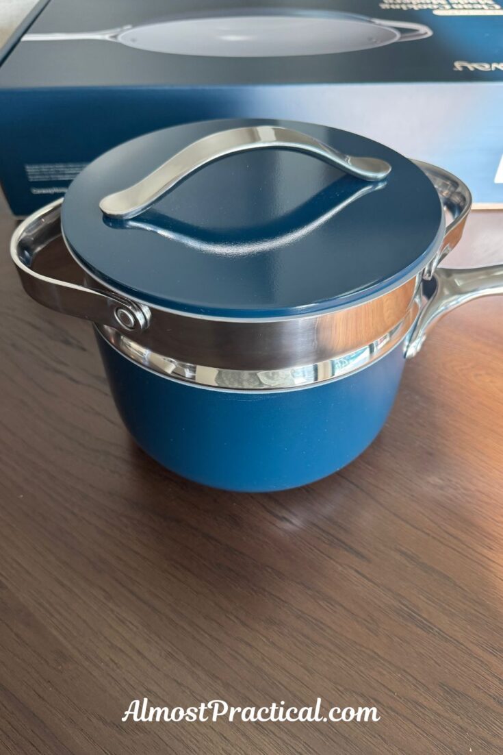 a photo of the Navy ceramic coated Caraway 3 quart saucepan with the steamer insert inside and the lid on top.