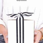 woman holding white gift box with black and white stripe ribbon